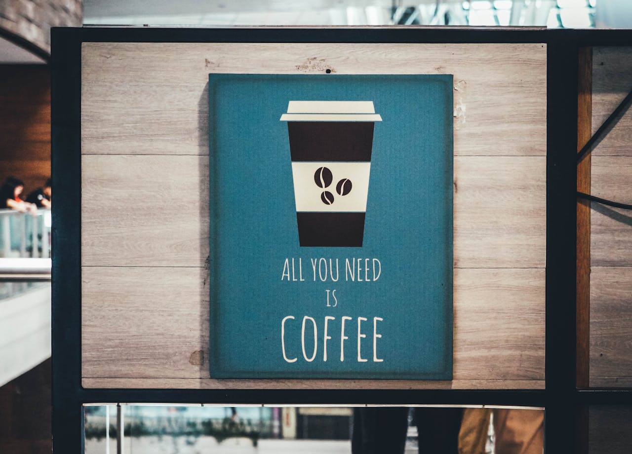 A decorative coffee-themed sign with inspiring text on a modern indoor display.